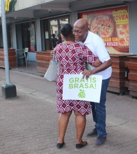 Een vrouw krijgt een gratis brasa van oud-DOE-voorzitter Carl Breeveld (foto: Regilio Derby)